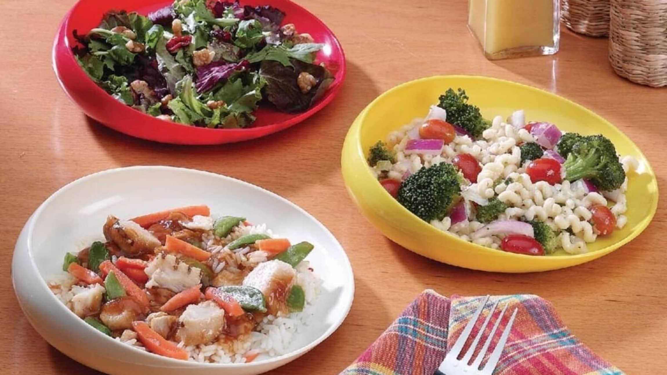 3 scoop bowls (red, yellow, and white)  with different foods in each of them.