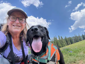 A woman and her dog take a selfie while hiking