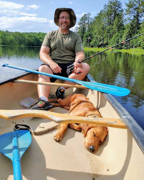 stand with me handler and dog in rowboat on lake