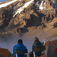 Hikers take a break to admire the views of Mt. Kilimanjaro.