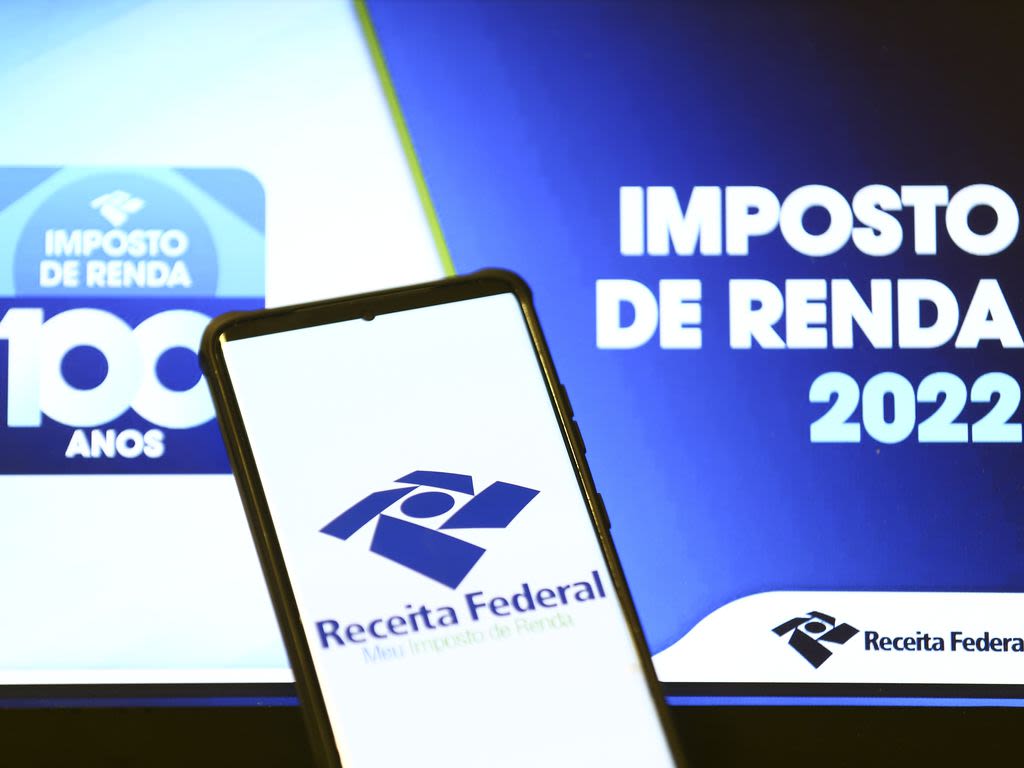 aplicativo da receita federal aberto em um smartphone com um letreiro do imposto de renda 2022 ao fundo