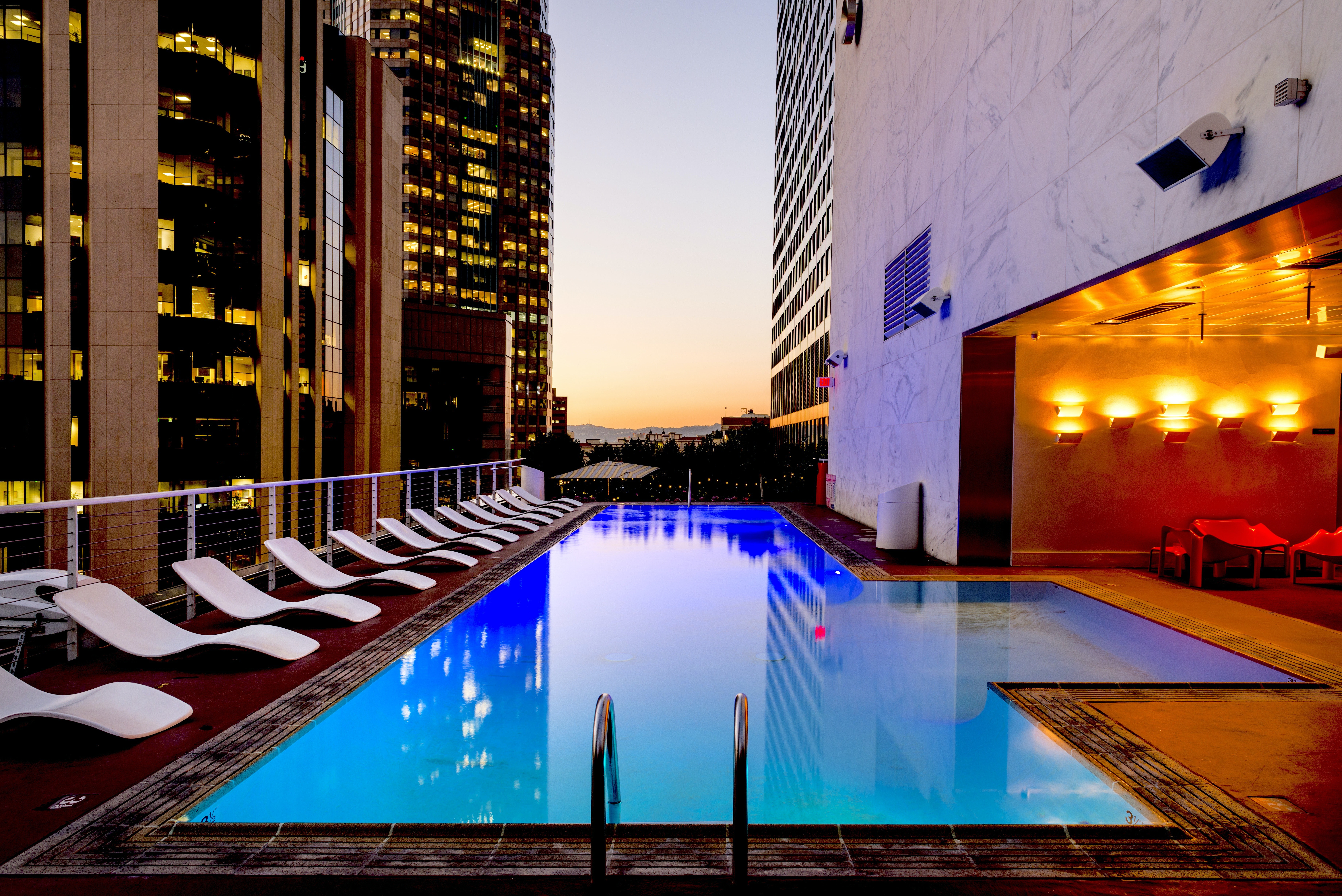 Casas de Luxo em SP: piscina e espreguiçadeiras no topo de um prédio no pôr do sol