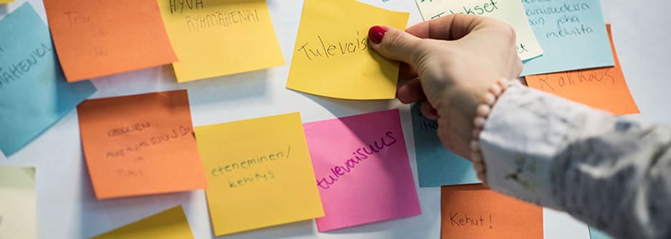 Uuden esihenkilön työkalupakki I Haaga-Helia Uuden esihenkilön käsi asettamassa post it -lappua seinälle