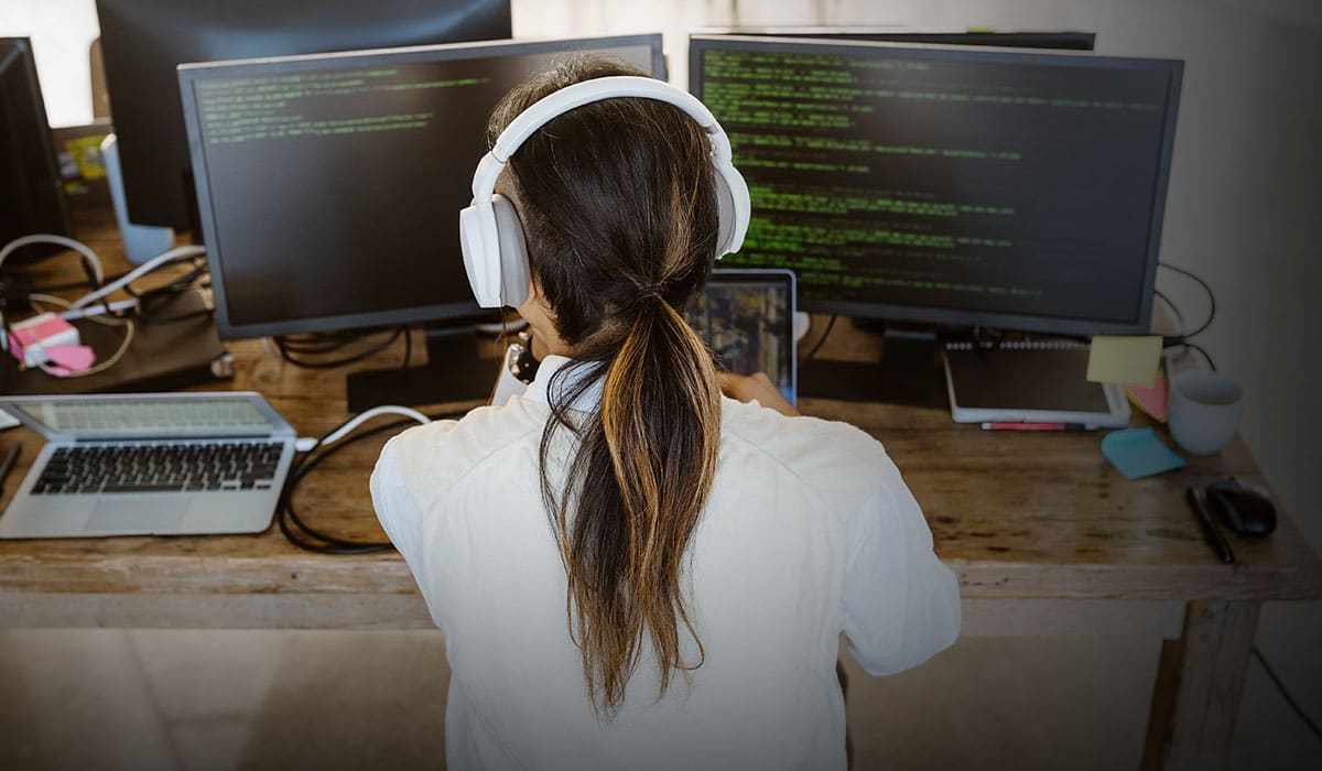 Person programmerar på dator med flera skärmar