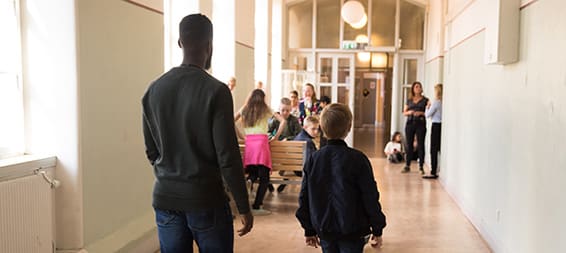 Löftadalens folkhögskola En vuxen person och ett barn går i en skolkorridor.