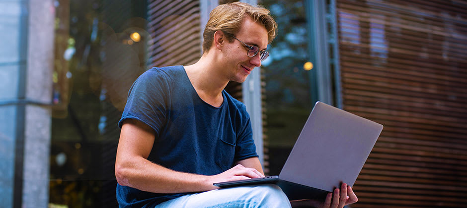 Leende man med laptop i knät