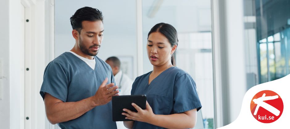 En manlig och kvinnlig undersköterska tittar på en patients hälsokontroll
