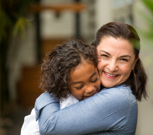 a mom and daughter hugging an smiling