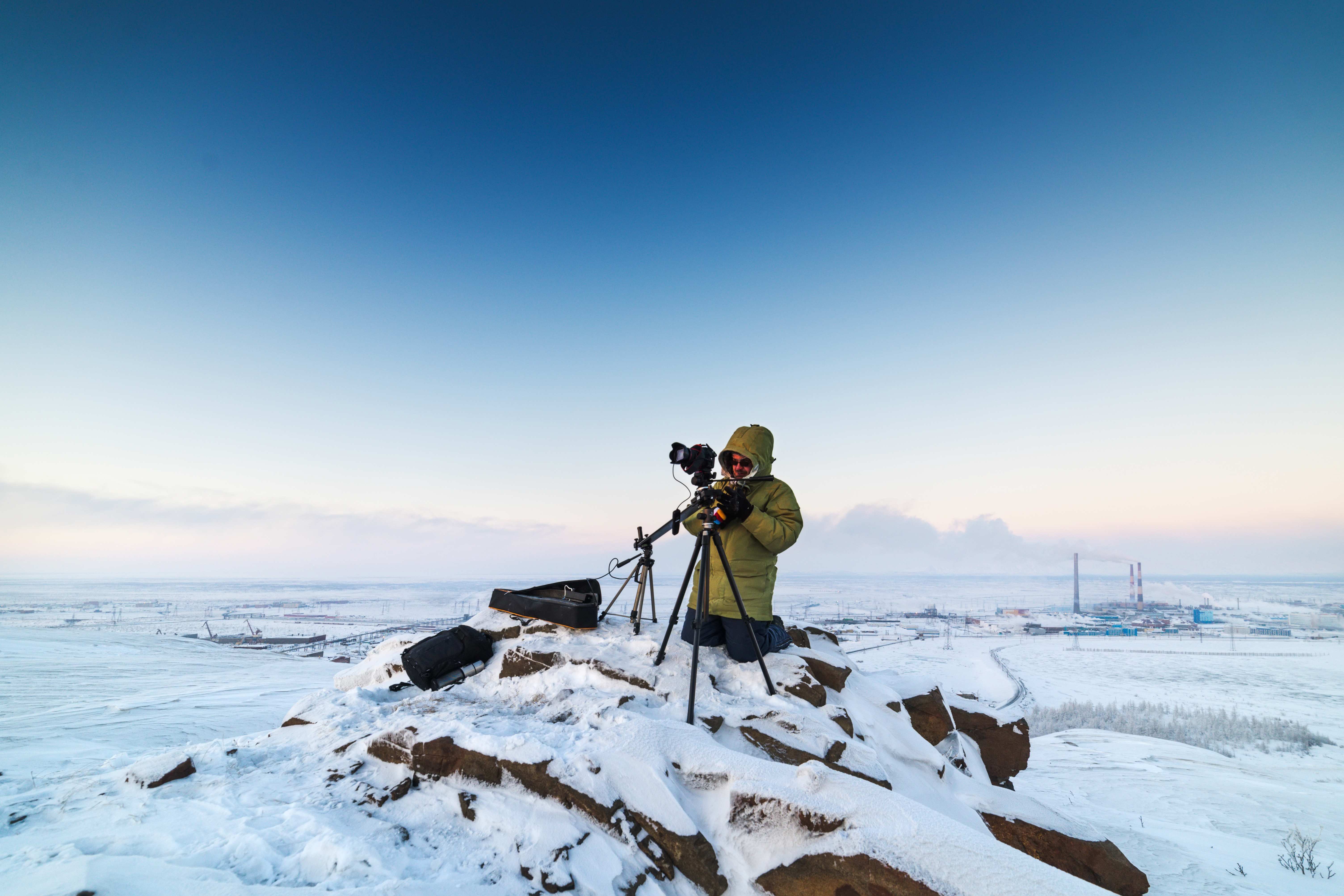 Man with photo camera on tripod taking timelapse photos in the arctic tundra.