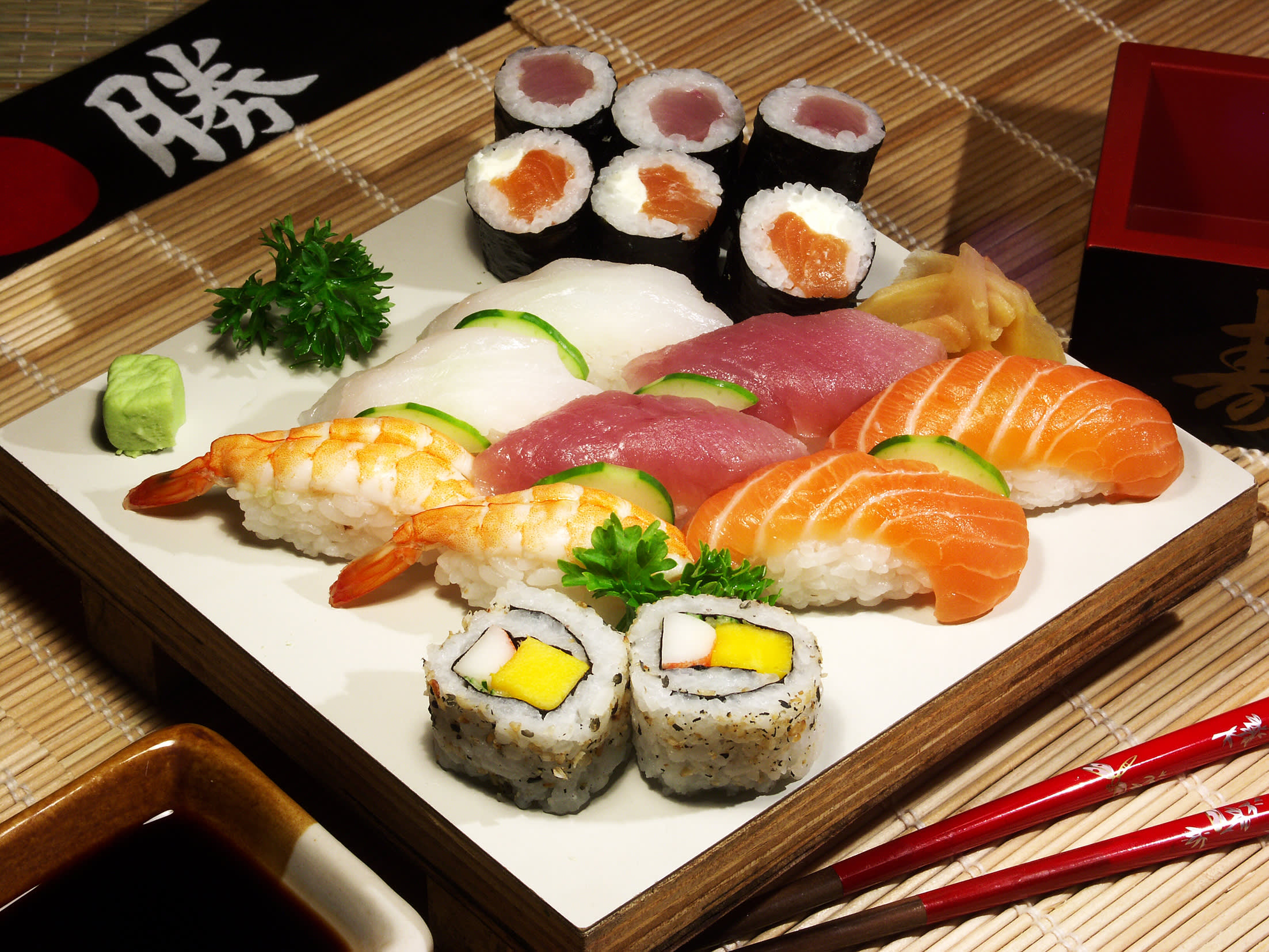 Sushiplatte mit Maki, Californiarolls mit Stäbchen auf einer Bambusmatte in Japan