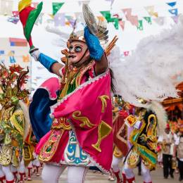 Enchanting Travels Bolivia Tours Oruro, Bolivia, carnival dancers wearing traditional masks and dresses on the street during the carnival