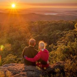 Paar sitzt am Felsrand und blickt in die Natur von Mount Kaputar in New South Wales, Australien