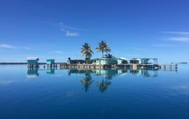 Hütten und Palmen im Wasser des Manihiki-Atolls der Cook-Inseln