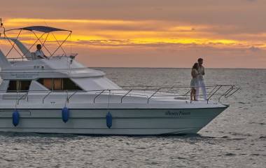 Junges Paar steht auf dem Deck einer Yacht bei Sonnenuntergang