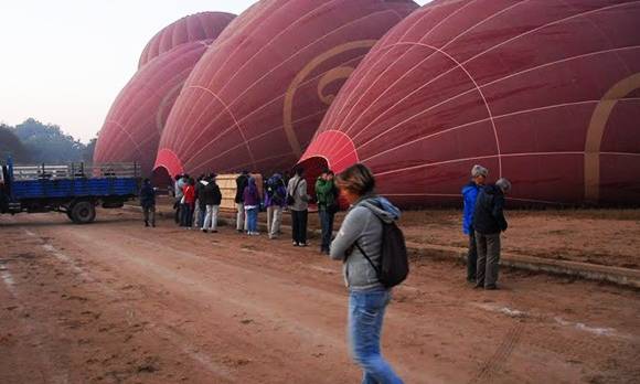 Touristen warten, währen die Heißluftballons in Bagan vor dem Abflug vorbereitet werden