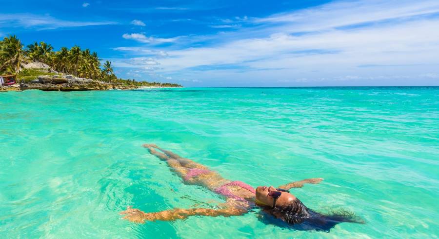 Enchanting Travels Mexico Tours relaxing in turquoise waters of Caribbean Sea in front of paradise beach in Tulum