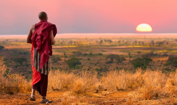 Masai warrior looks out over Serengeti at sunset, Africa, shutterstock_142942633