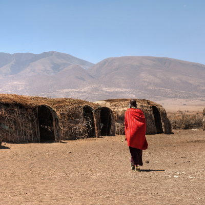 Massai huts with a woman in red in back view