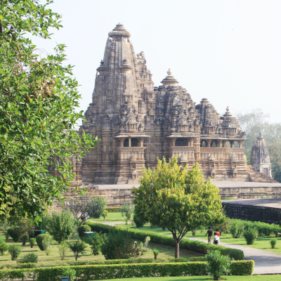 Blick auf einen von Grünflächen umgebenen Tempel in Khajuraho Indien