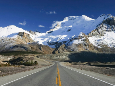 a snow covered road with a mountain in the background