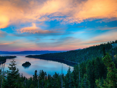 Lake Tahoe water body surrounded by green covers and a clear blue sky