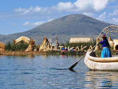 a small boat in a body of water with Lake Titicaca in the background