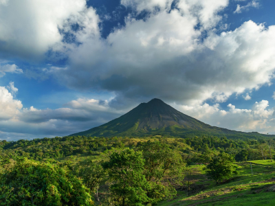 a large green field with a mountain in the background