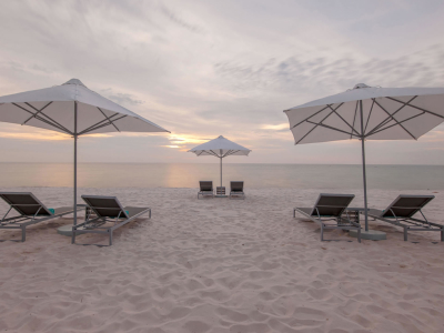 a couple of lawn chairs sitting on top of a sandy beach