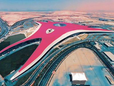 a train is parked on the beach with Ferrari World Abu Dhabi in the background