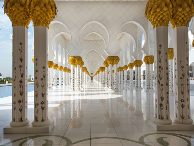 a clock hanging from the ceiling with Sheikh Zayed Mosque in the background