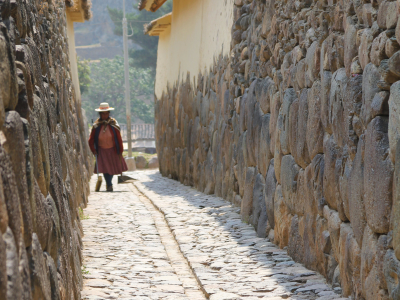 a person walking down a sidewalk next to a stone wall