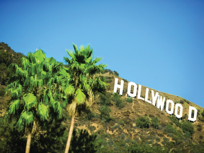 a sign in front of a tree with Hollywood Sign in the background