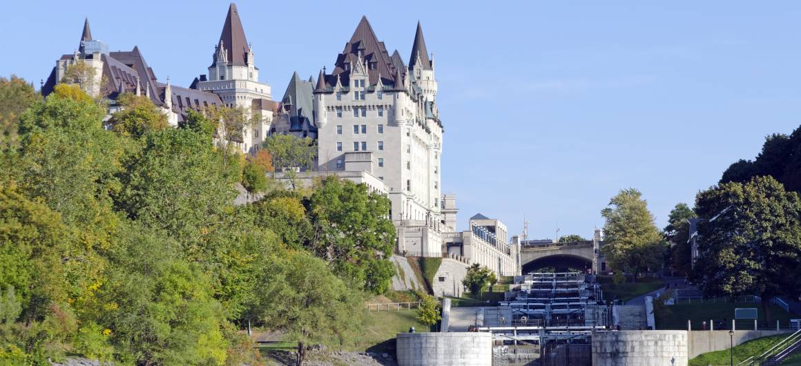 View of Parliament Hill in Ottawa with a boat navigating the locks of the Rideau Canal below the historic buildings.