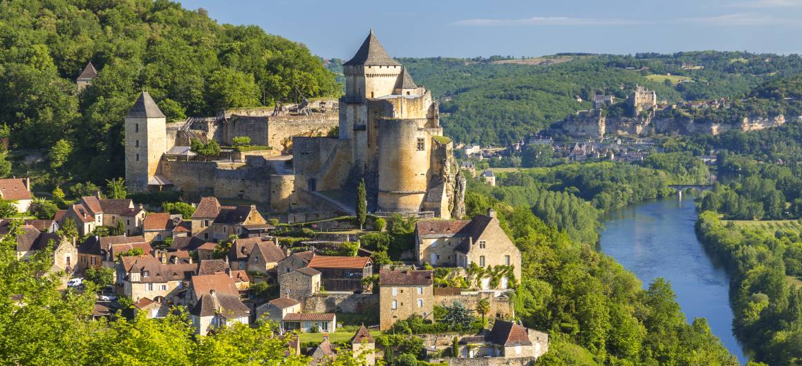 Un château médiéval perché au-dessus d’une rivière et d’un village perché en Aquitaine.