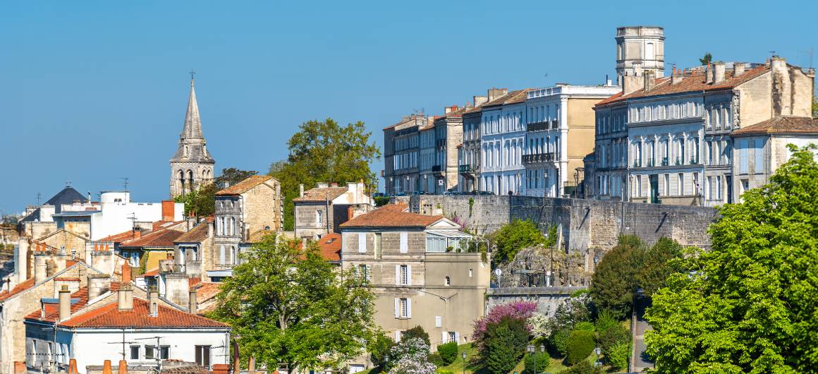 Panoramisch uitzicht over de daken van Angoulême, met historische gebouwen en tuinen die langs een heuvel afdalen onder een strakblauwe hemel.