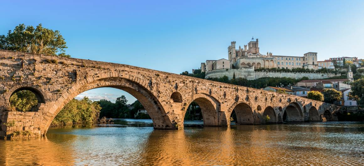 The historic stone bridge in Béziers spans the Orb River with Saint-Nazaire Cathedral in the background, offering a striking cultural landmark along the Canal du Midi.