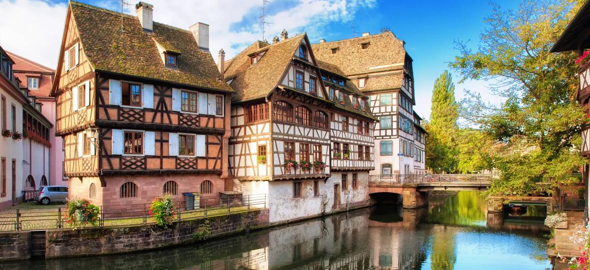 Traditional timber-framed houses reflecting in the calm canal waters in the historic Petite France district of Strasbourg.