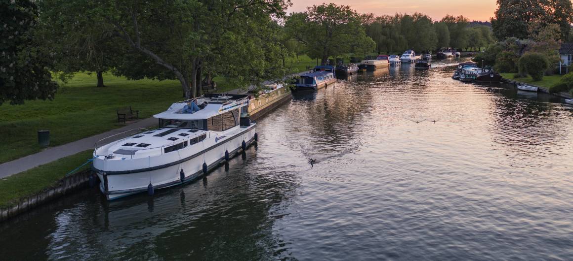 Bateaux amarrés sur la Tamise au coucher du soleil, scène paisible du soir dans la campagne anglaise.