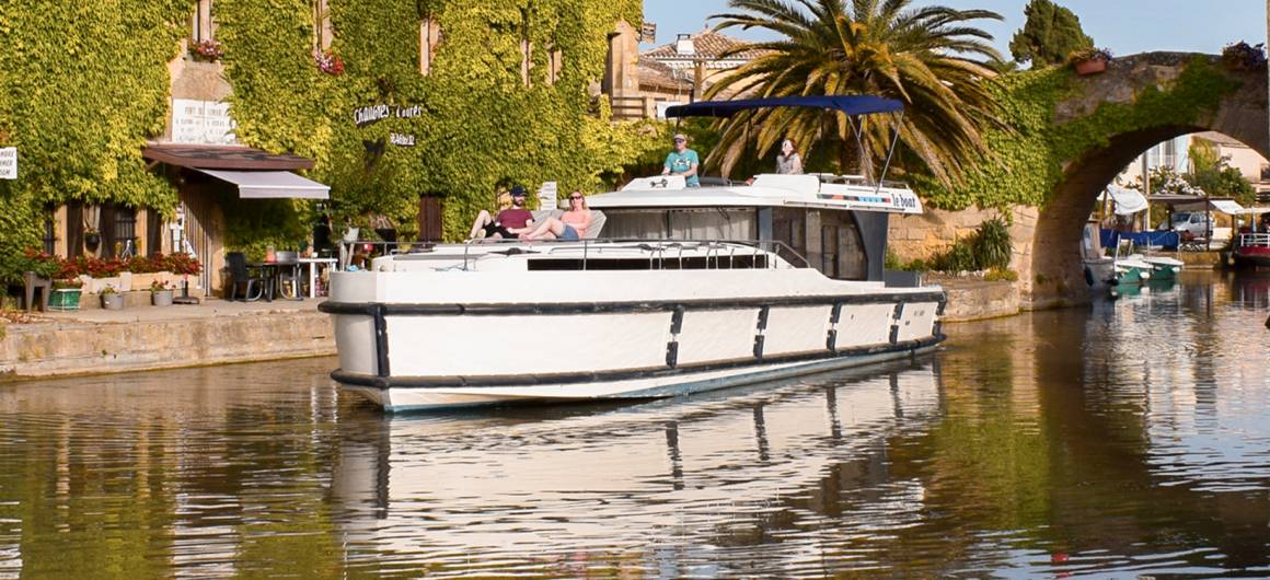Holidaymakers enjoy a leisurely boating escape on the Canal du Midi, winding through vineyards and villages in the French countryside.