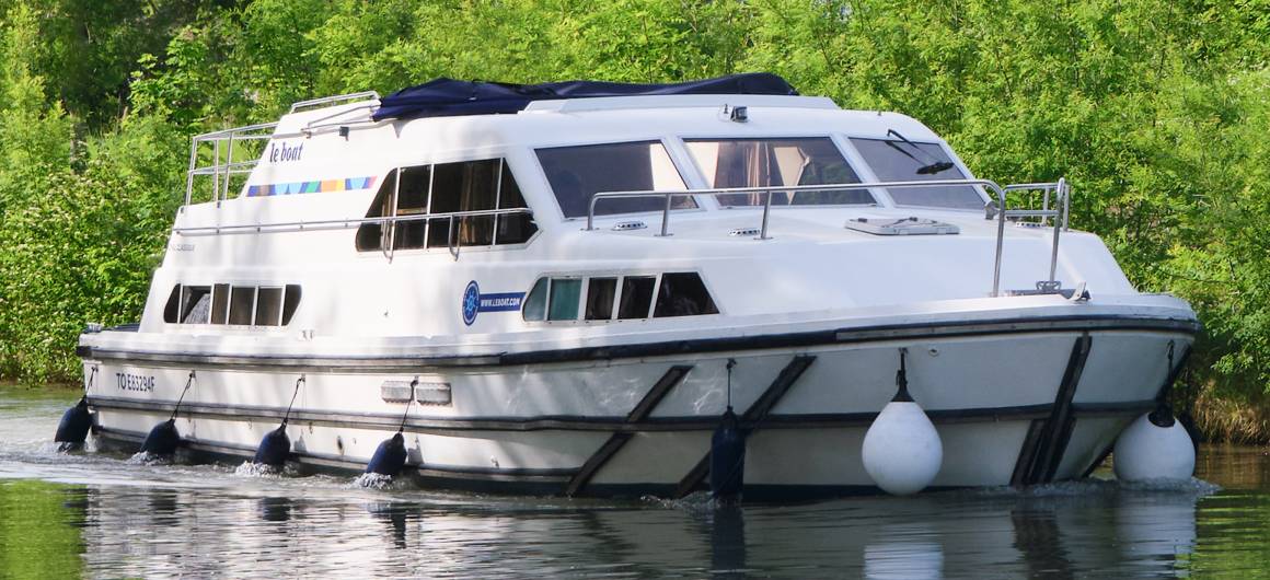 Side profile of Royal Classique navigating through lush, peaceful waterways.