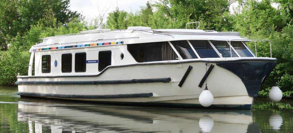 Side view of the Vision 4 gliding along the water surrounded by lush green trees.
