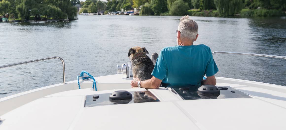 Homme et chien naviguant sur la Tamise, croisière tranquille, propice au brouillard dans la campagne de la vallée de la Tamise.