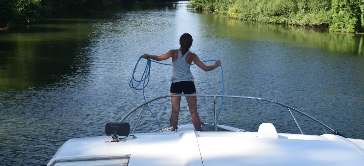 Femme s’apprêtant à amarrer un bateau sur la Tamise, expérience nautique pratique en Angleterre.
