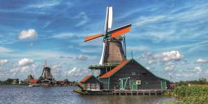 Traditionele Nederlandse molens aan de oever onder een dramatische lucht in Zaanse Schans.