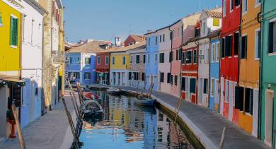 Un canal étroit bordé de maisons colorées et de petites embarcations dans les rues paisibles de Burano.
