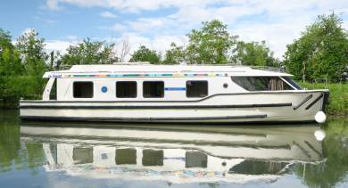 Vision cruising along a scenic canal, reflected beautifully in the calm water.