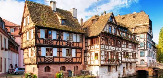 Traditional timber-framed houses reflecting in the calm canal waters in the historic Petite France district of Strasbourg.