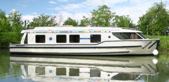 Vision 4 cruising along a scenic canal, reflected beautifully in the calm water.