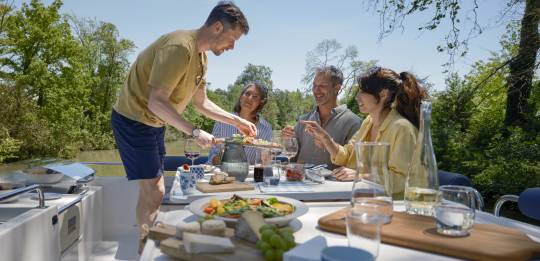 Friends enjoying alfresco dining on a luxury canal boat in the heart of nature.