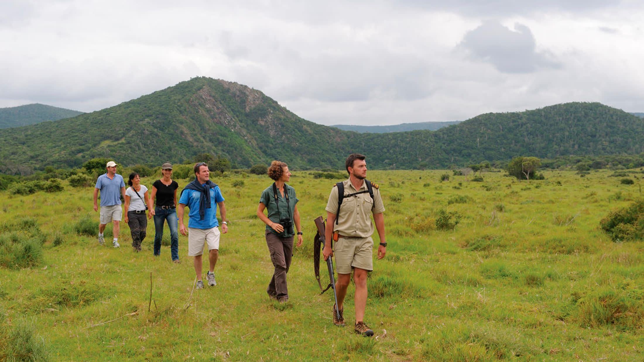 a group of people in a field with a mountain in the background